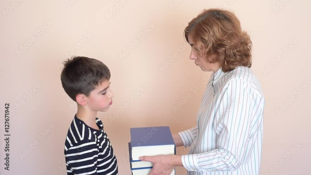 Woman showing young boy books which he needs to read Woman showing young boy books which he needs to read
