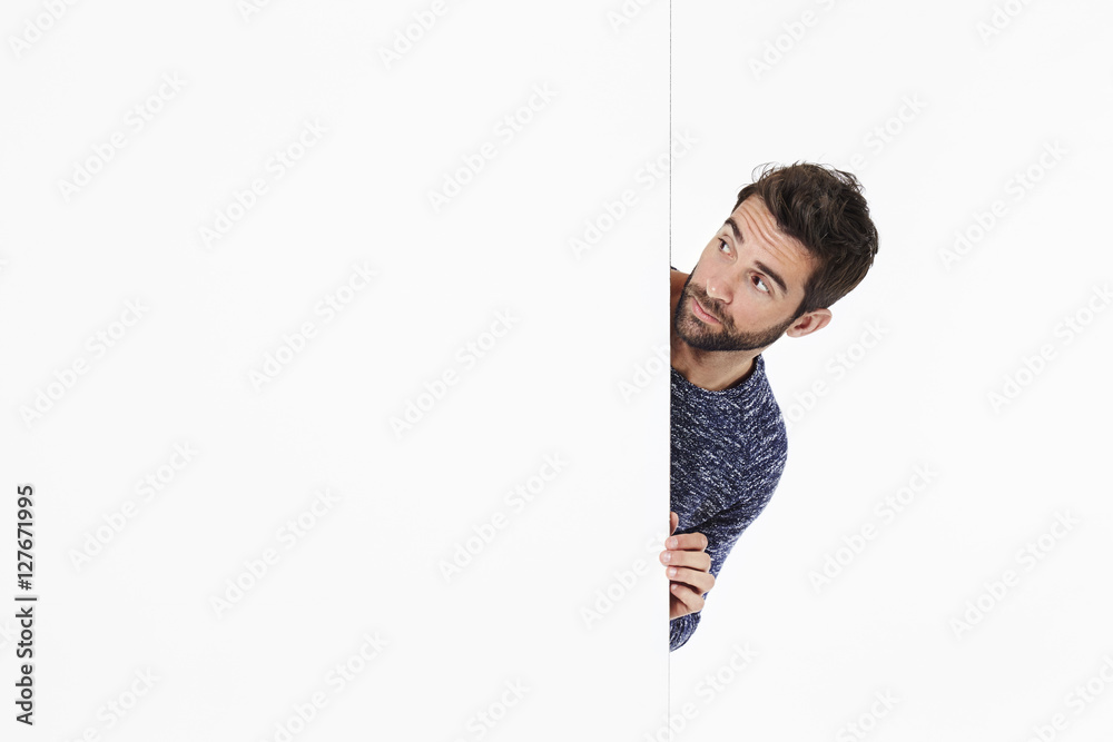 Curious guy looking around white wall Curious guy looking around white wall