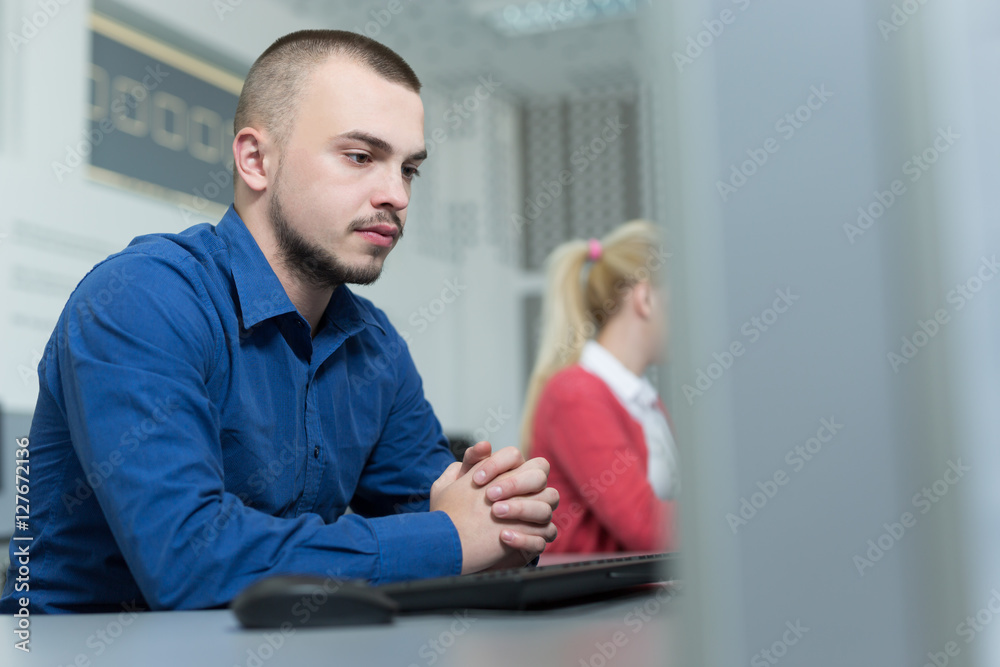 Fototapeta premium Handsome young businessman working at his desktop computer sitti