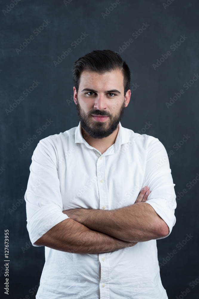 Portrait of a  young bearded man against black chalkboard