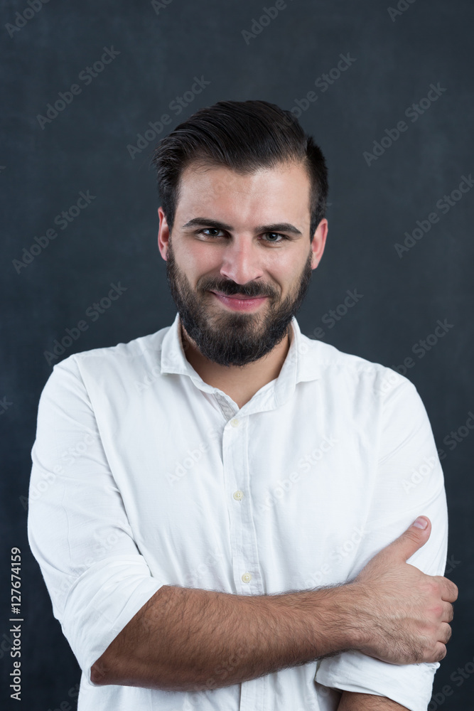 Portrait of a  young bearded man smiling against black chalkboar