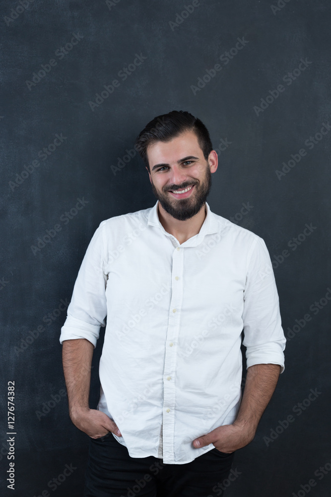 Portrait of a young bearded man against black chalkboard Portrait of a young bearded man against black chalkboard