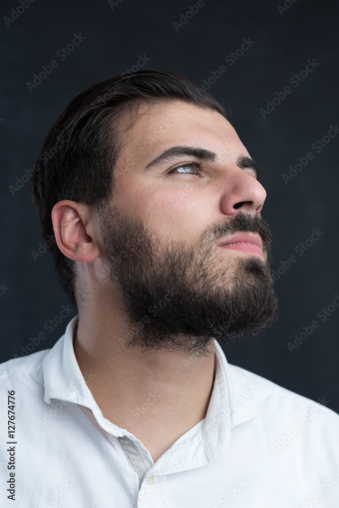 Obraz premium Portrait of a young bearded man thinking against black chalkboa