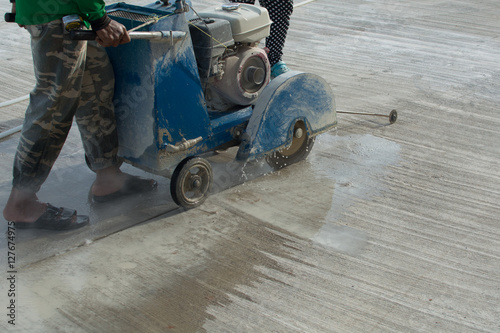 Workers on a road construction use a blade cuting floor