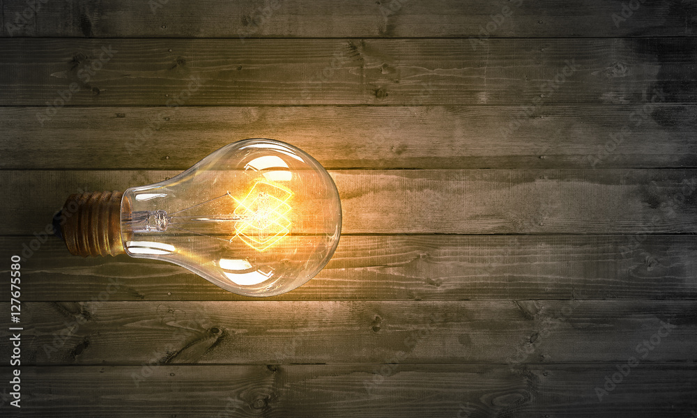 Light bulb on wooden surface . Mixed media Light bulb on wooden surface . Mixed media