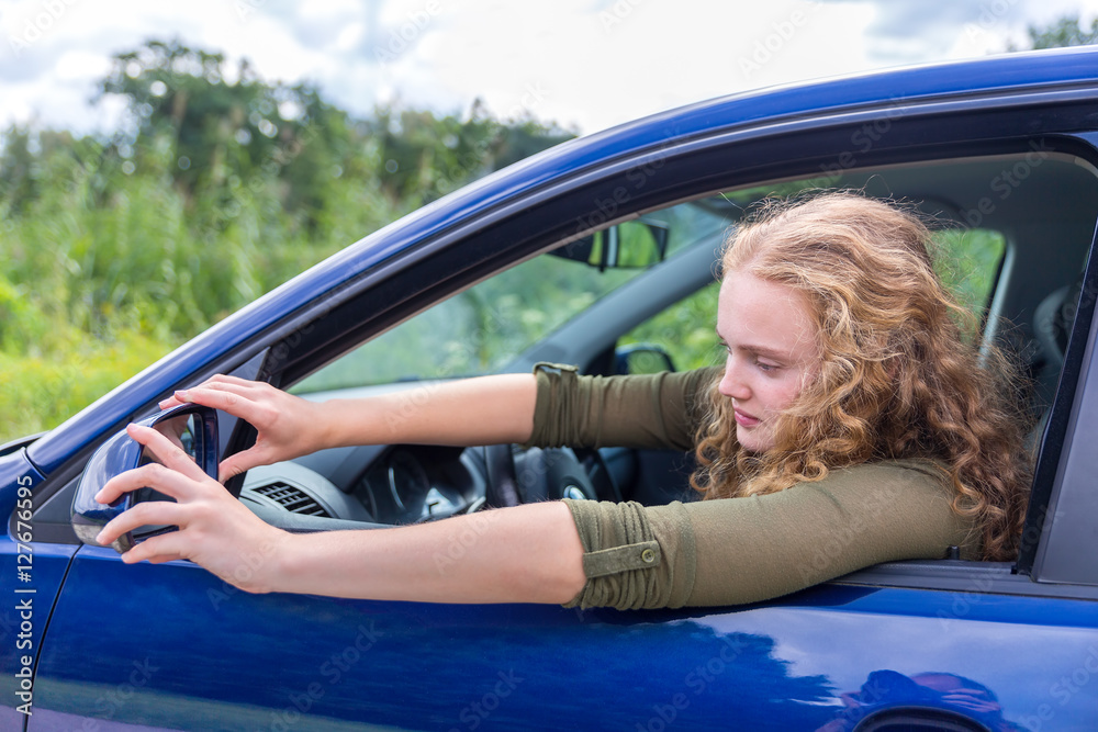 Caucasian woman adjusting side mirror of car