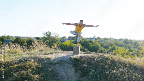 Young sporty man standing at yoga pose outdoor. Caucasian guy pr