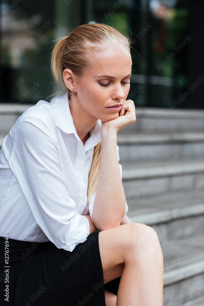 Portrait of a thoughtful business woman sitting on the stairs Portrait of a thoughtful business woman sitting on the stairs
