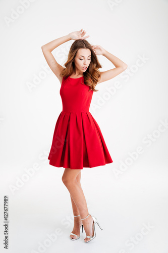 Pretty brunette woman in red dress posing with raised hands