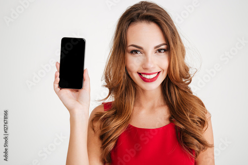 Smiling woman in red dress showing blank smartphone screen
