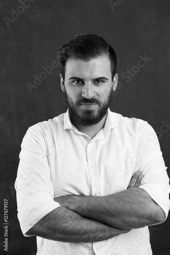 Portrait of a young bearded man against black chalkboard