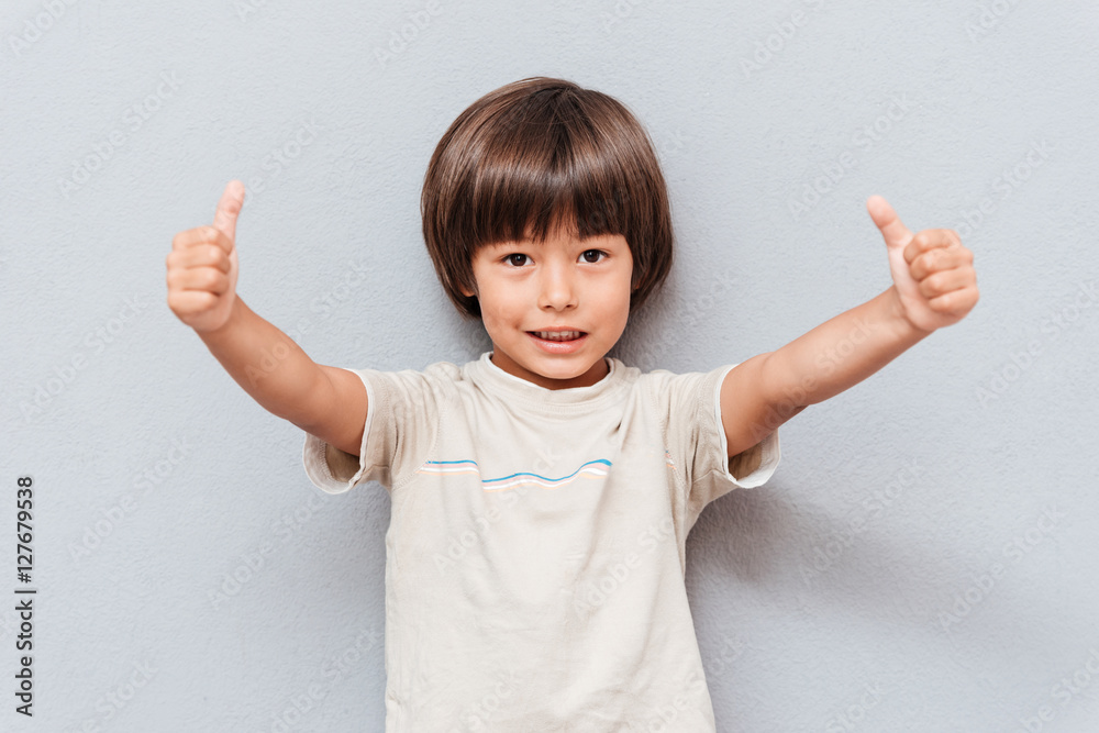 Happy little boy standing and showing thumbs up Happy little boy standing and showing thumbs up