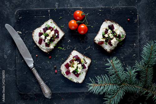 Vegan sandwiches with roasted beet and goat cheese on wooden cutting board, top view