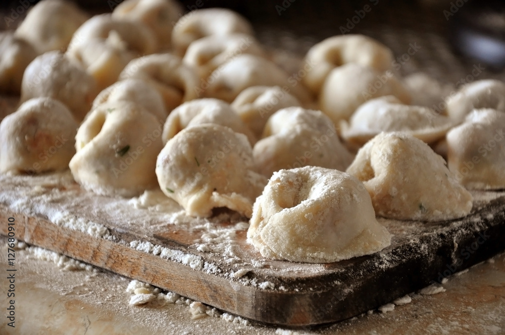 The process of preparation of Russian meat dumplings. Homemade raw dumplings with flour on a wooden board. Close-up.