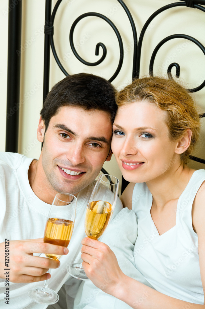 Young happy amorous couple celebrating with champagne at bedroom. Love, relations, holidays, romantic concept shot. Young happy amorous couple celebrating with champagne at bedroom. Love, relations, holidays, romantic concept shot.
