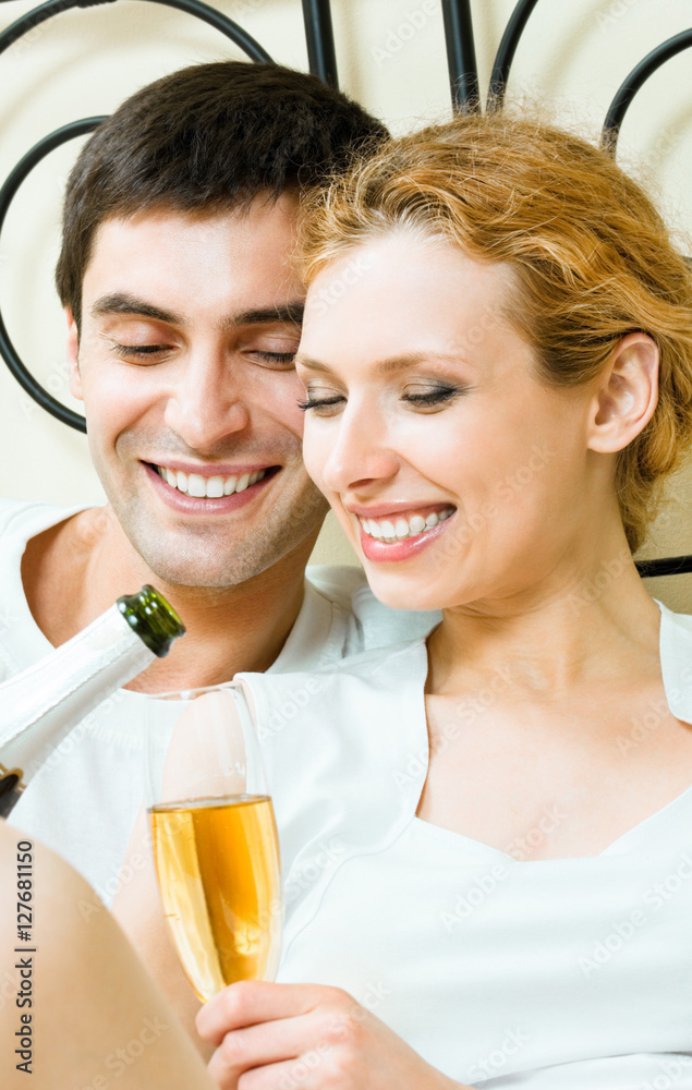 Young happy amorous couple celebrating with champagne at bedroom. Love, relations, holidays, romantic concept shot. Young happy amorous couple celebrating with champagne at bedroom. Love, relations, holidays, romantic concept shot.
