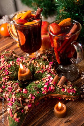 Christmas mulled wine with fruits and spices on wooden table. Xmas decorations in background. Two glasses. Winter warming drink  recipe ingredients around.