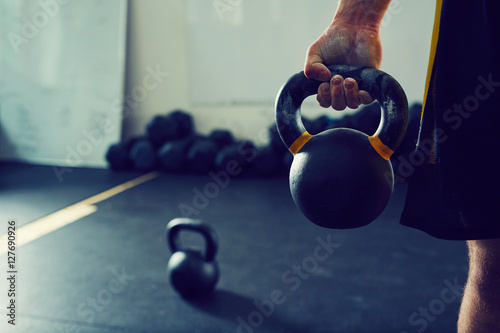 Close-up of athletic man holding kettlebell weight at gym