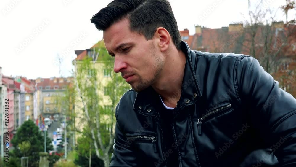 Young handsome sad man sits on bench and thinks in park - detail of face express Young handsome sad man sits on bench and thinks in park - detail of face express