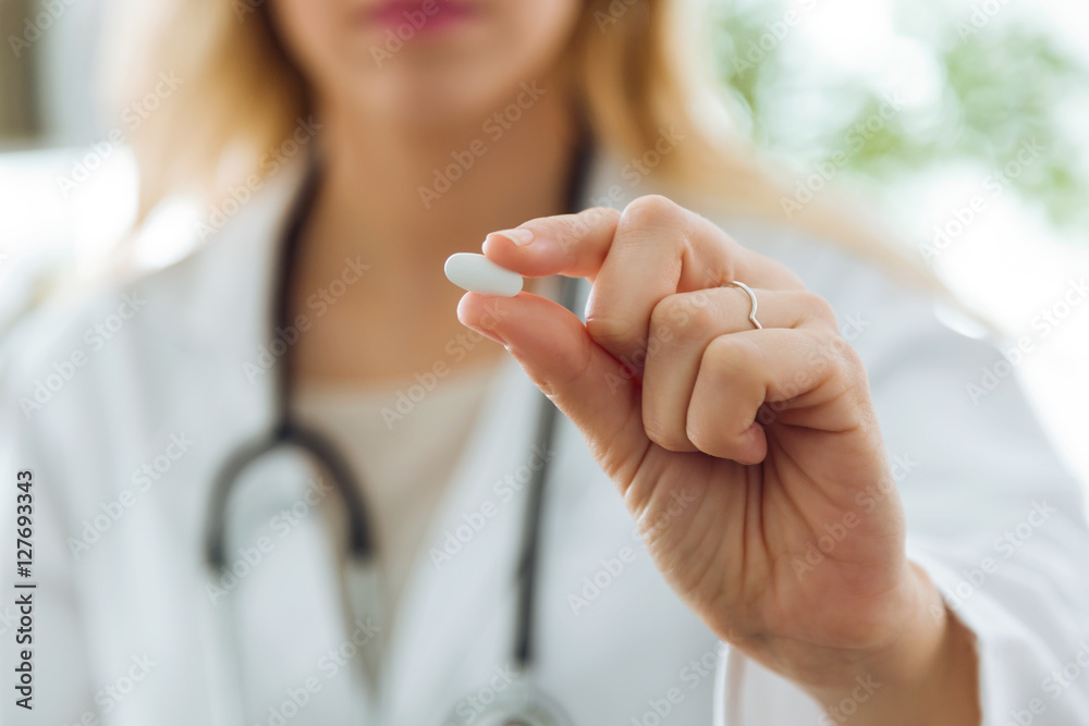 Female doctor giving you a pill. - obrazy, fototapety, plakaty 