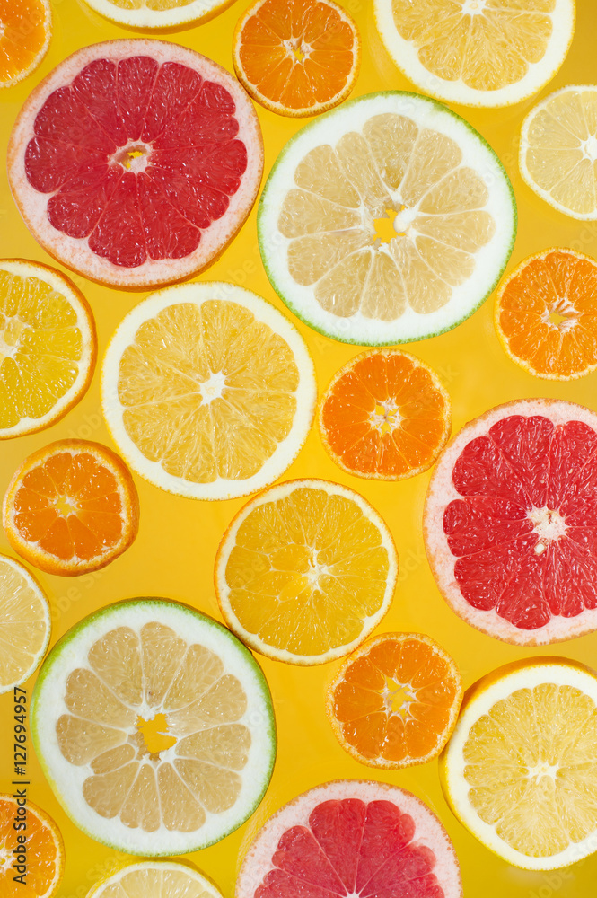 Slices of citrus fruits on the bright yellow background Slices of citrus fruits on the bright yellow background