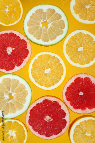 Slices of citrus fruits on the bright yellow background