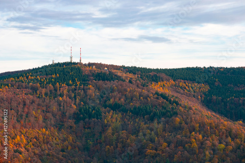 Telecommunication towers on the summit of the hill covered with colorful fall forest