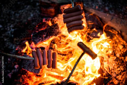 Принти на полотні Making and cooking Hot dog sausages over open camp fire.