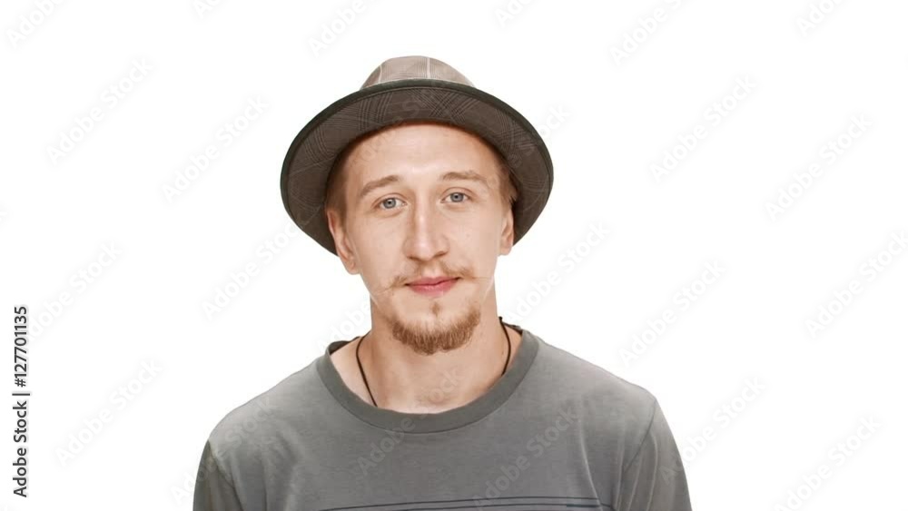 Young handsome man in hat smiling over white background. Slow motion. Young handsome man in hat smiling over white background. Slow motion.