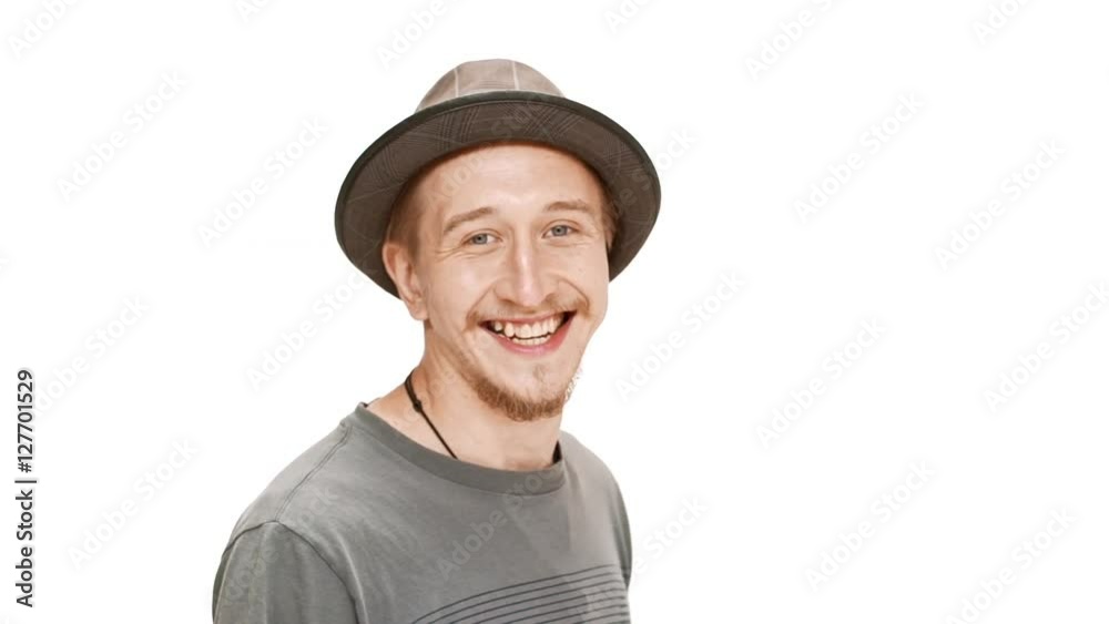 Young handsome man in hat smiling, passing by over white background. Slow motion. Young handsome man in hat smiling, passing by over white background. Slow motion.