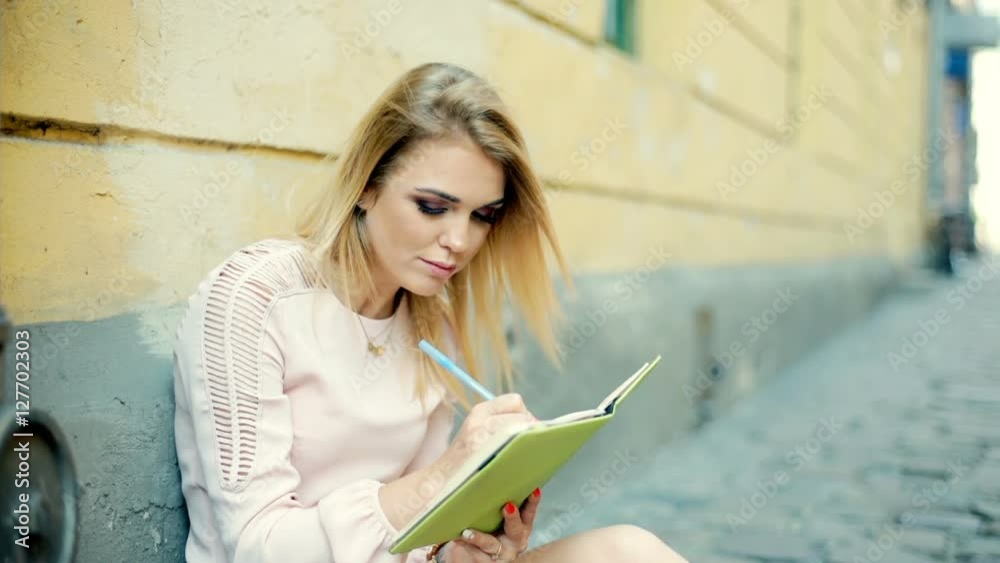 Happy girl looking thoughtful while writing something in her journal
Happy girl looking thoughtful while writing something in her journal