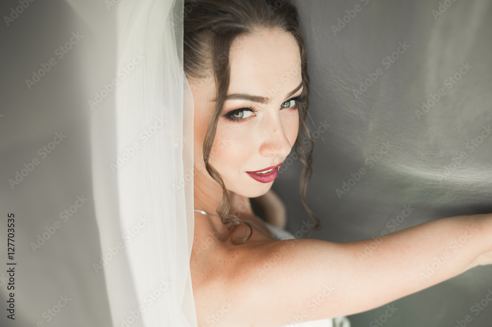 Beautiful young bride with makeup and hairstyle in bedroom, newlywed woman final preparation for wedding. Happy girl waiting groom. Portrait soft focus Beautiful young bride with makeup and hairstyle in bedroom, newlywed woman final preparation for wedding. Happy girl waiting groom. Portrait soft focus