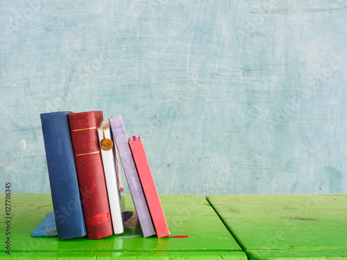 Stack of book on wooden green table with blackboard backhround photo