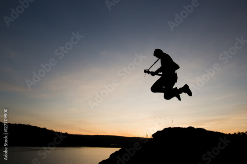 Silhouette man jumping with playing guitar in the sunset or sunrise