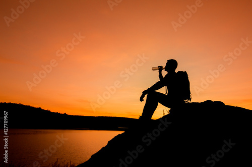 Silhouette of man with backpack drinking water, travel