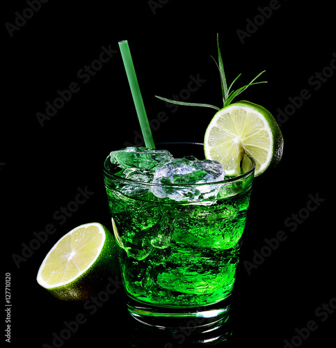 Green tarragon drink with ice cubes, lime on a black background