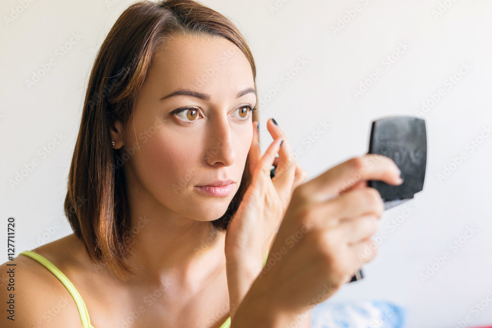 The girl does makeup on her face