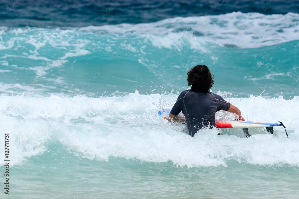 Surfer with surfboard going to the sea at surf spot. Phuket Island.