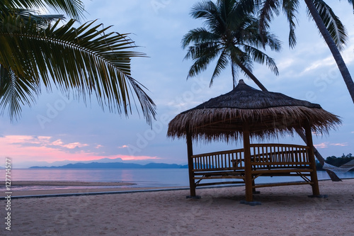 Cottage and coconut tree against beach at sunrise background.