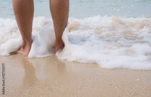Man leg standing on beach and was hit by ripples wave, wet 