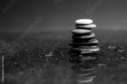 Photo Pebble stack in black and white with black pebbles and one white on the top lyin
