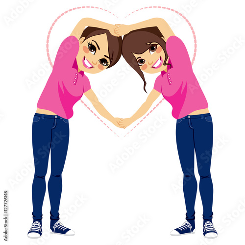 Two beautiful young girls making love shape with arms together with pink shirt uniform and blue jeans on valentine day