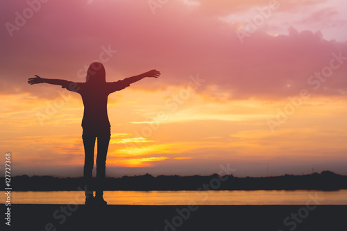 Fototapeta Naklejka Na Ścianę i Meble -  Silhouette of woman standing riverside and beautiful sunset back