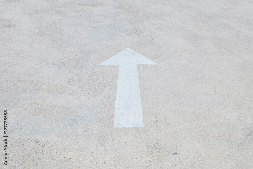 Fototapeta premium Closeup white painted arrow sign on cement street floor textured background