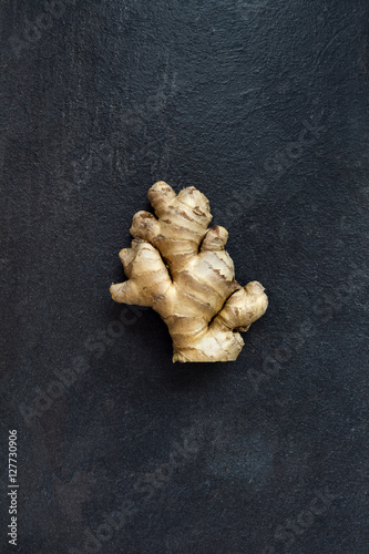 Single brown ginger root isolated on gray slate stone background