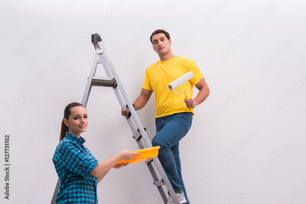 Young couple painting wall at home Young couple painting wall at home