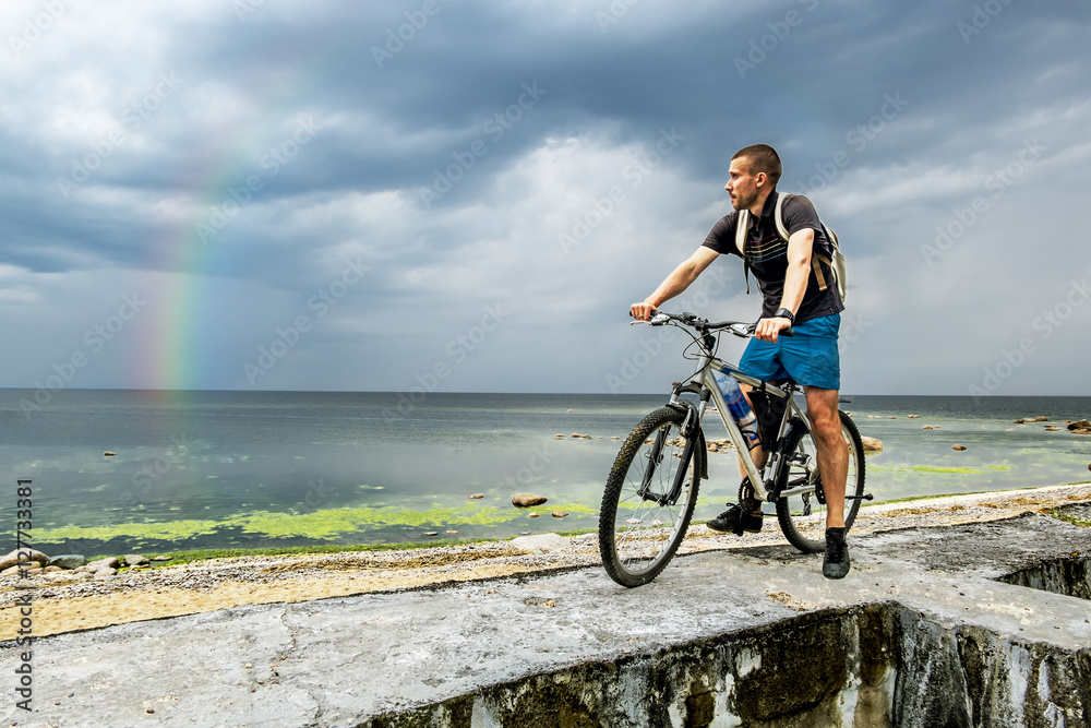 Fototapeta premium The cyclist with his bike looking at the horizon of the sea and