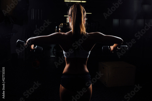 Beautiful fitness woman with lifting dumbbells .