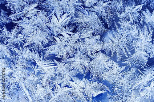 beautiful festive frosty pattern with white snowflakes on a blue background o...