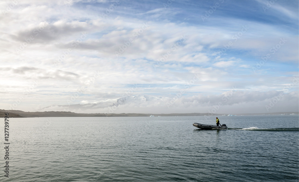 Fototapeta premium JOKULSARLON GLACIER LAGOON, ICELAND-OCTOBER 08: Unidentified man drives a pontoon boat on October 08,2016 in Jokulsarlon glacier lagoon, Iceland